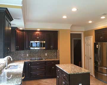 A large kitchen with black-brown drawers and doors